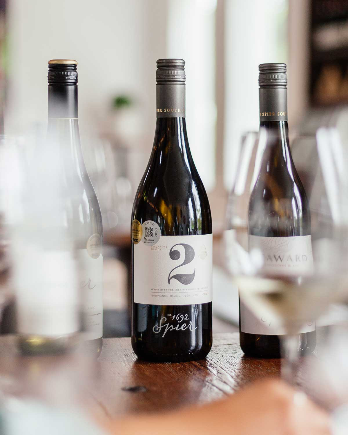 Eine Flasche Spier Creative Block 2 Weißwein mit einem weißen Etikett mit einer großen Zahl 2, goldener Schrift und einem schwarzen Schraubverschluss. Auf dem Etikett steht, dass es sich um eine Mischung aus Sauvignon Blanc und Semillon handelt.