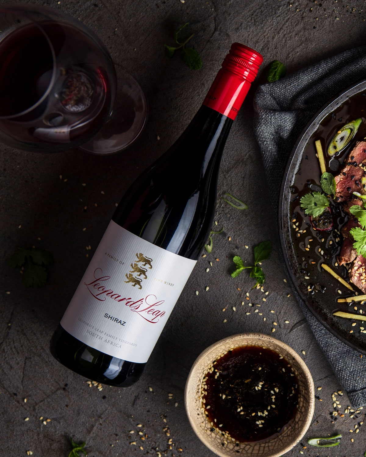 Eine Flasche Leopard's Leap Shiraz Rotwein mit einem roten Schraubverschluss und einem weißen Etikett mit goldener und roter Schrift und einem goldenen Leoparden-Emblem. Auf dem Etikett steht, dass er aus Südafrika stammt.