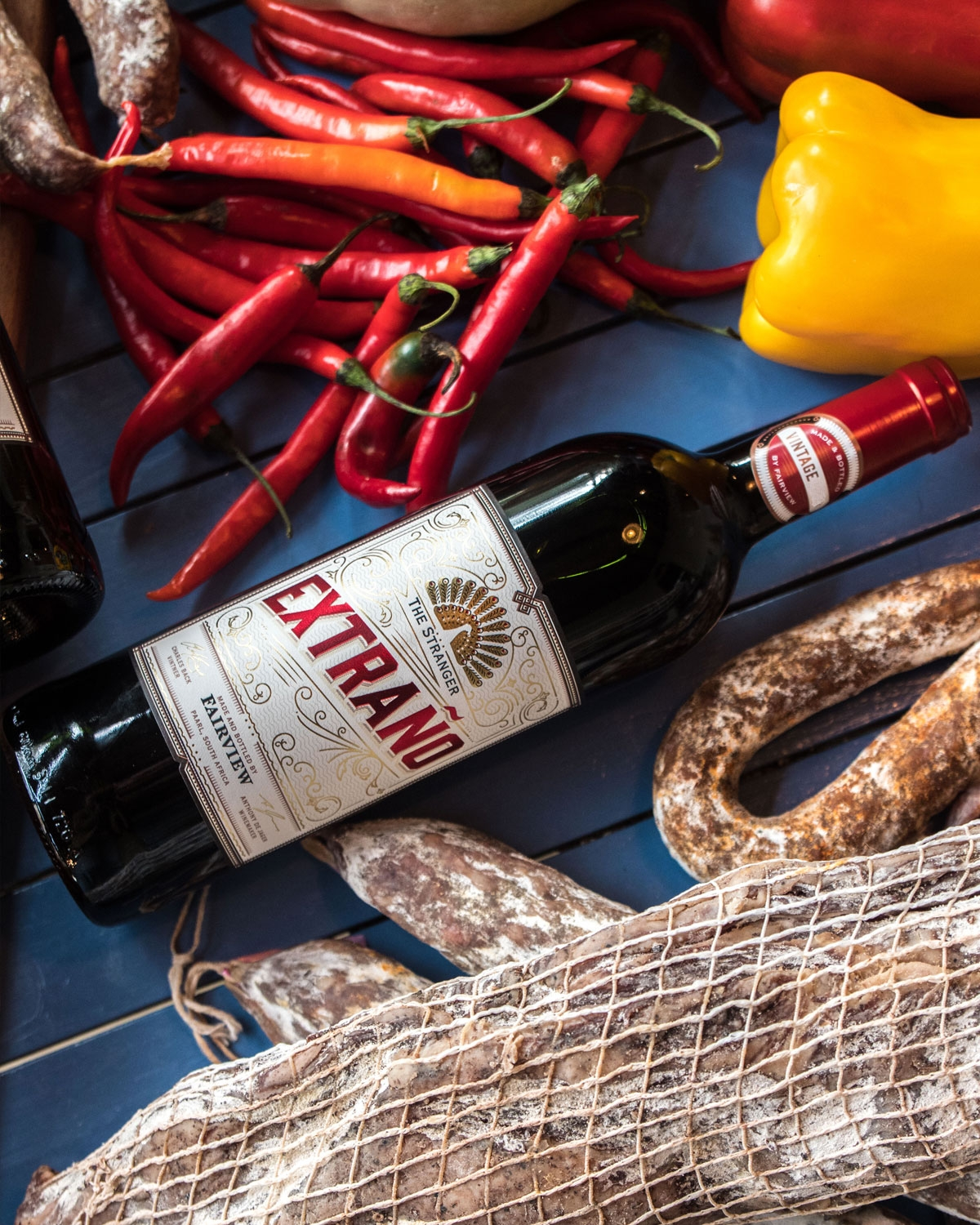Eine Rotweinflasche mit der Aufschrift EXTRAÑO, mit goldenen und roten Akzenten, dem Branding von The Stranger und Fairview und einer roten Folienkapsel am Hals.