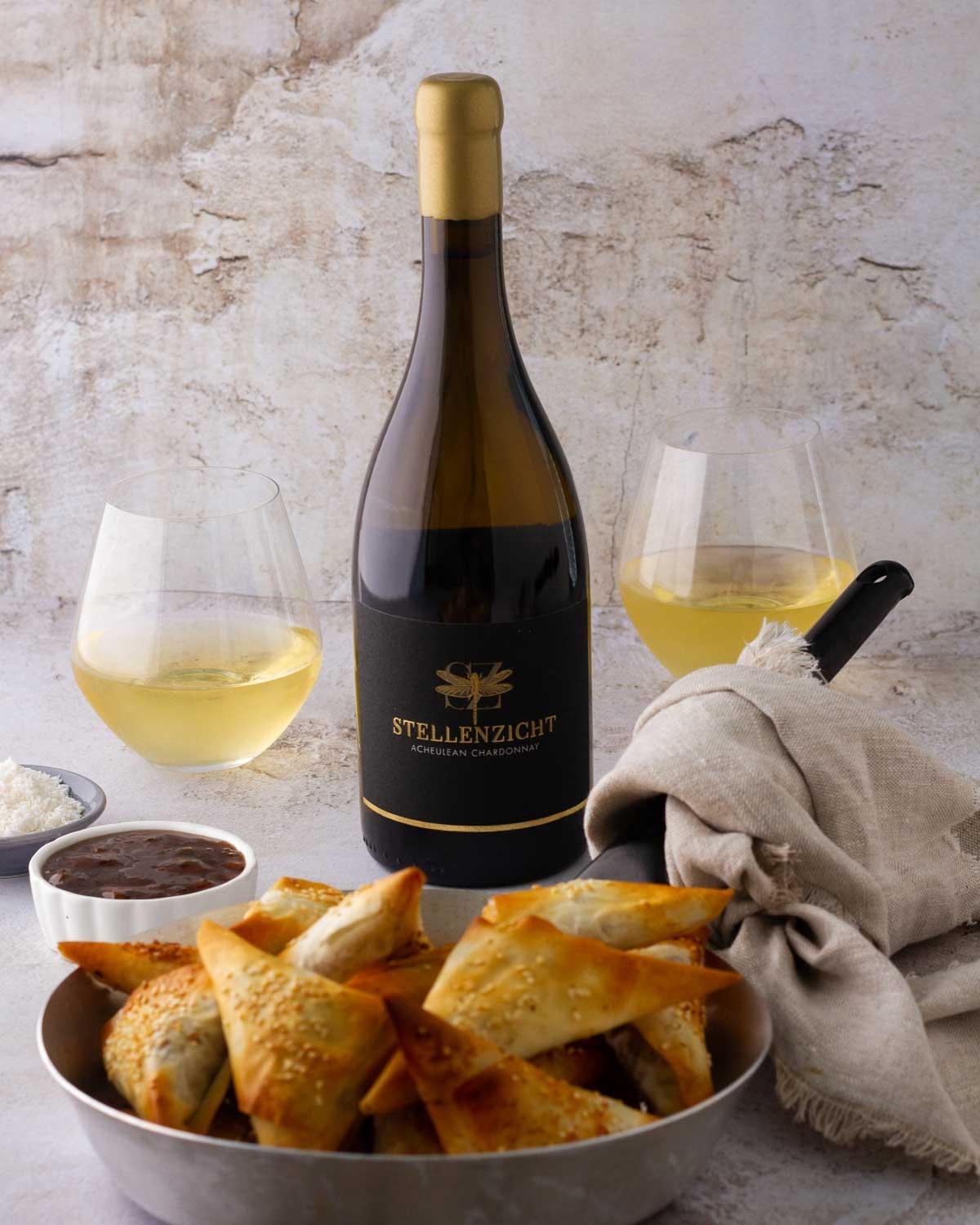 Weinflasche mit Goldfolienverschluss und schwarzem Etikett mit goldenem Libellenmotiv und dem Text STELLENZICHT ACHEULEAN CHARDONNAY in goldener Schrift.