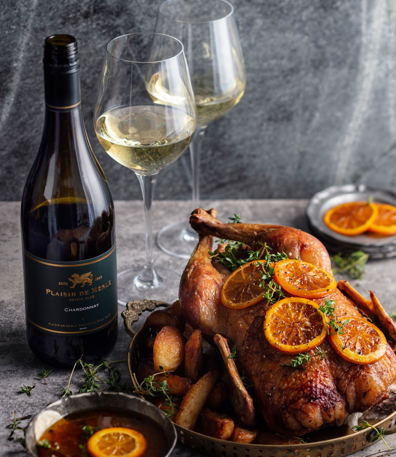 Eine Flasche Plaisir de Merle Estate Wine Chardonnay mit einem dunklen Etikett mit goldener Schrift und einem Löwenemblem. Die Flasche steht aufrecht vor einem weißen Hintergrund.