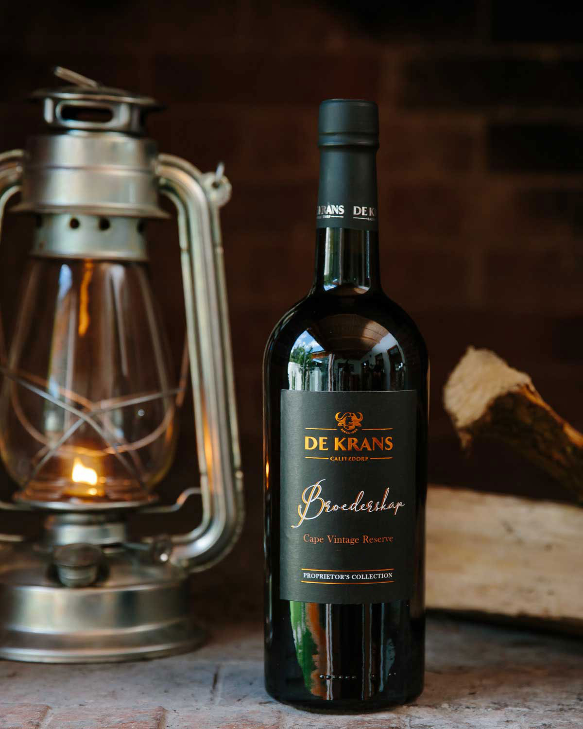Eine Flasche De Krans Broederskap Cape Vintage Reserve aus dunklem Glas mit einem schwarz-orangefarbenen Etikett mit goldener Schrift und der Aufschrift Proprietors Collection am unteren Rand.