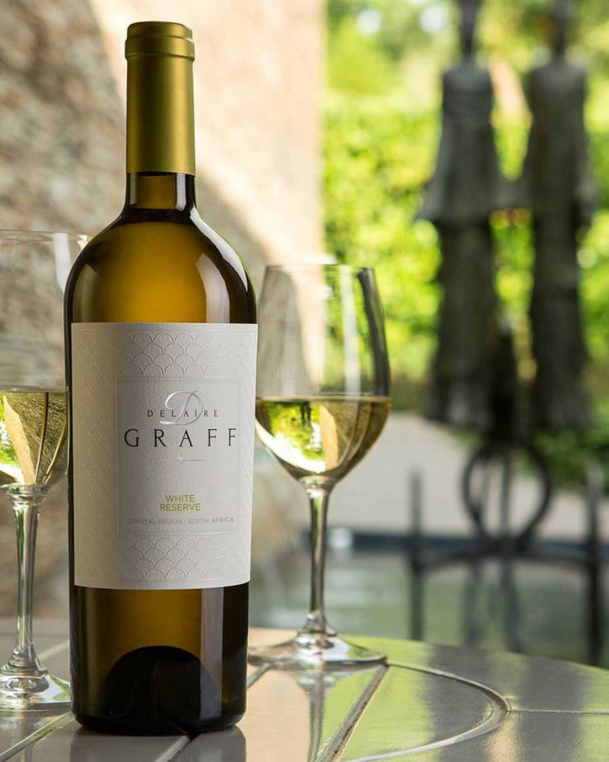 Eine Flasche Delaire Graff White Reserve Wein mit Goldfolie und einem weißen Etikett mit dem Markennamen und der Herkunft, aus Western Cape, Stellenbosch.