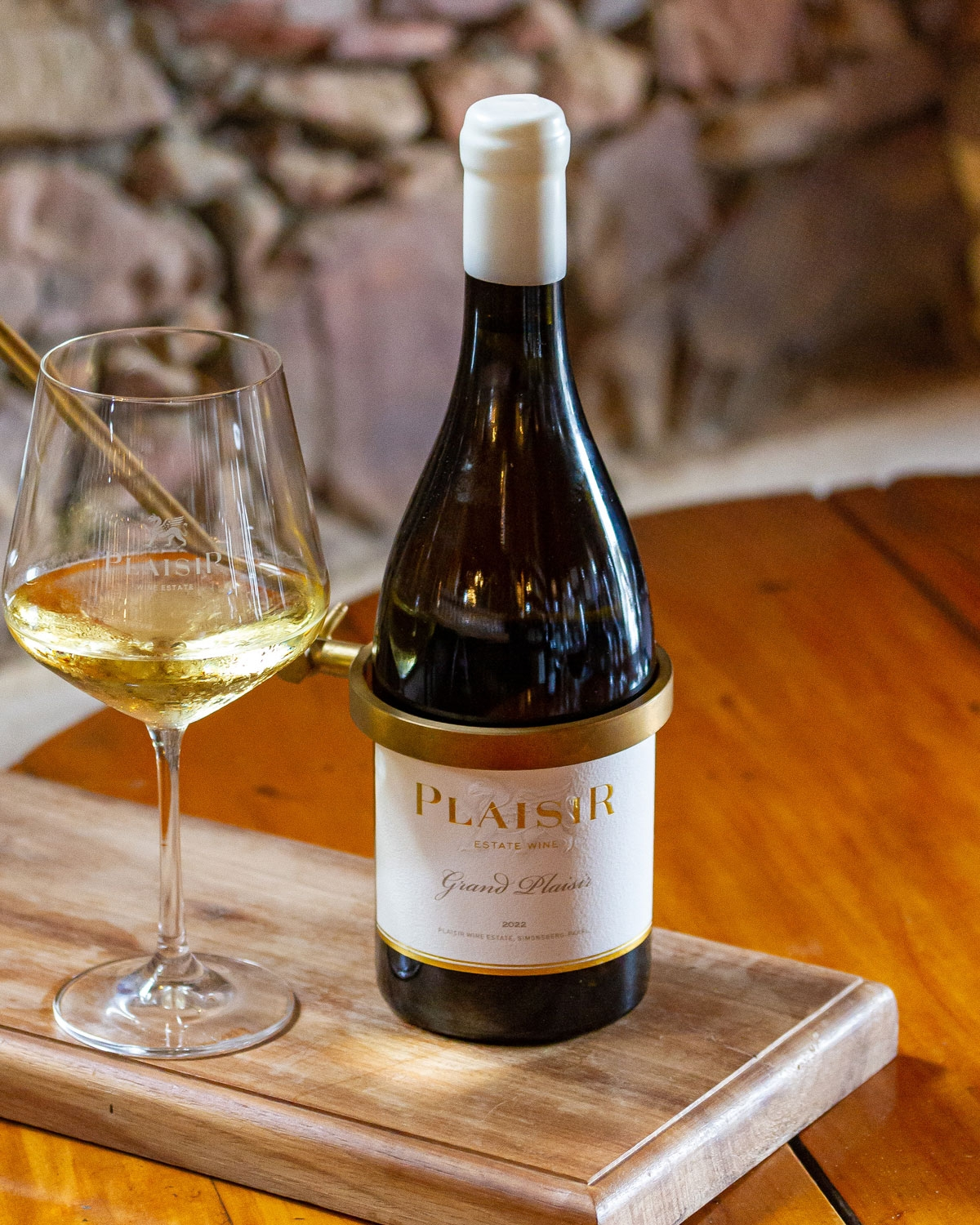 Eine Flasche des Weins Plaisir Estate Grand Plaisir mit einem weiß-goldenen Etikett und einem weißen Folienverschluss vor einem schlichten weißen Hintergrund.