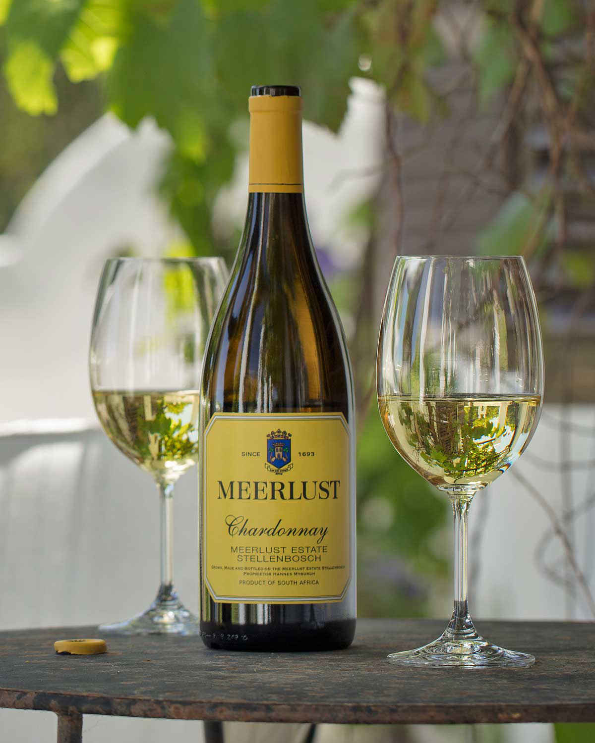Eine Flasche Meerlust Chardonnay Wein mit einem gelben Etikett und Deckel. Das Etikett enthält das Meerlust-Wappen und den Text "Meerlust Chardonnay, Meerlust Estate, Stellenbosch, Product of South Africa".