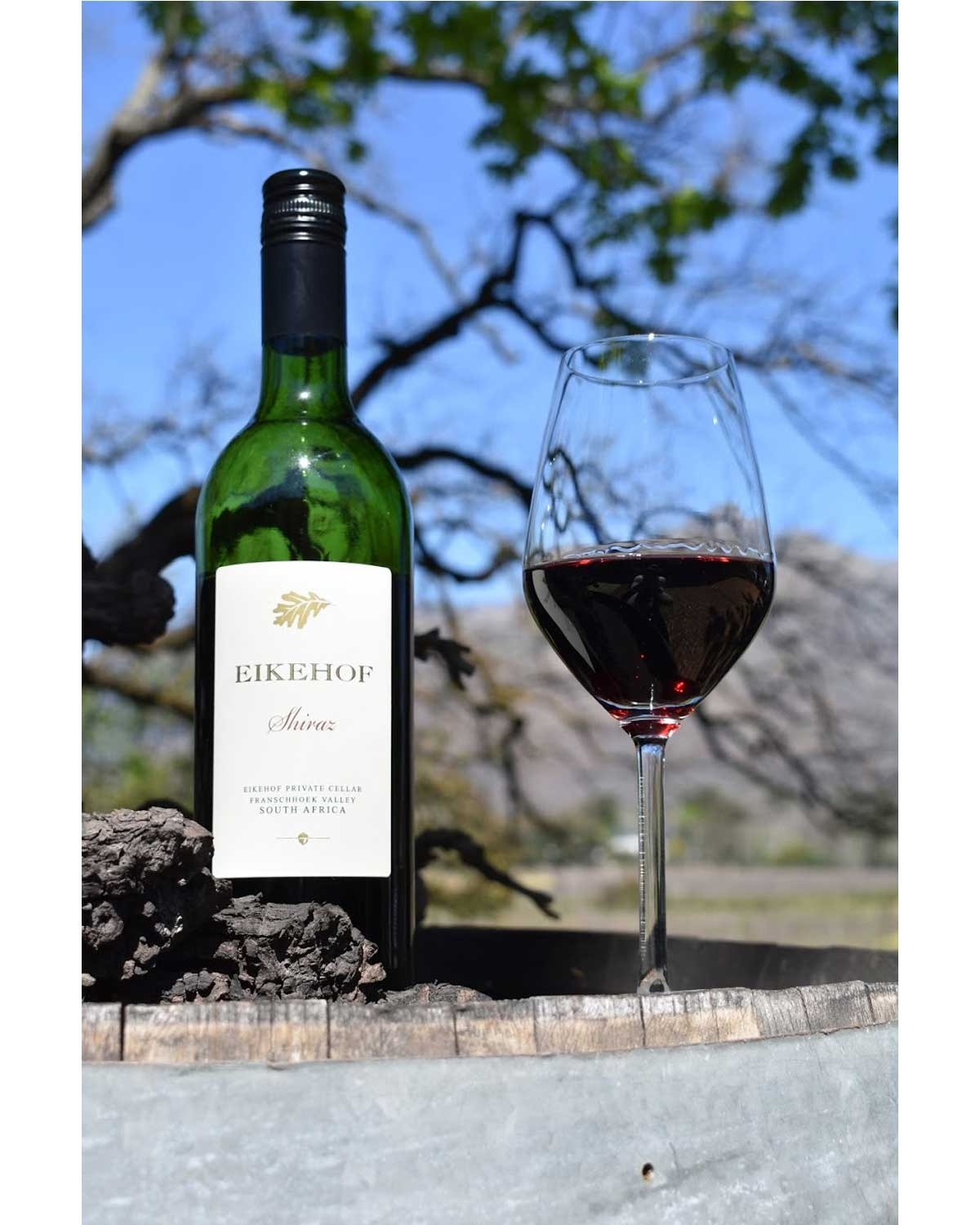 Eine Weinflasche aus dunklem Glas mit einem cremefarbenen Etikett mit der Aufschrift Eikehof Shiraz und einer Abbildung eines Eichenblatts, hergestellt von Eikehof Private Cellar in Franschhoek Valley, Südafrika.