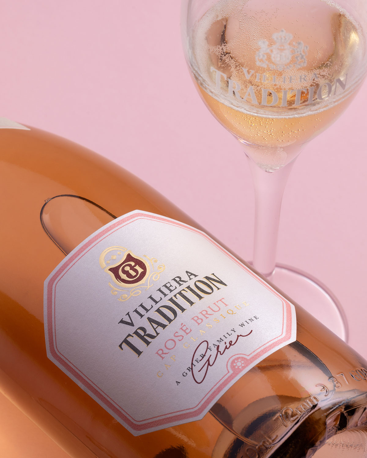 Eine Flasche Villiera Tradition Rosé Brut Sekt mit einem mit Goldfolie umwickelten Hals, einem rosa-weißen Etikett und einem rosa Schleifen-Siegel im oberen Bereich.