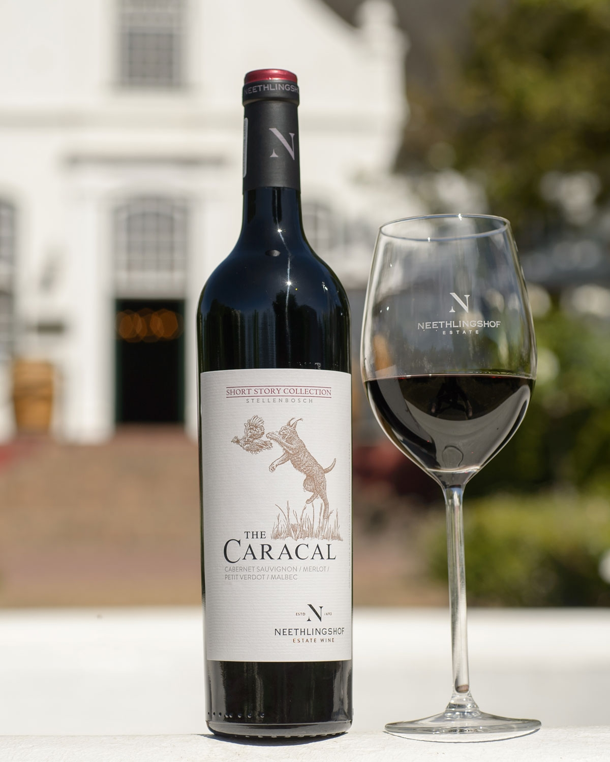 Eine Flasche des Rotweins Neethlingshof The Caracal mit einem Etikett, auf dem ein Karakal abgebildet ist, der einen Vogel fängt. Der Wein stammt aus der Short Story Collection, Stellenbosch.