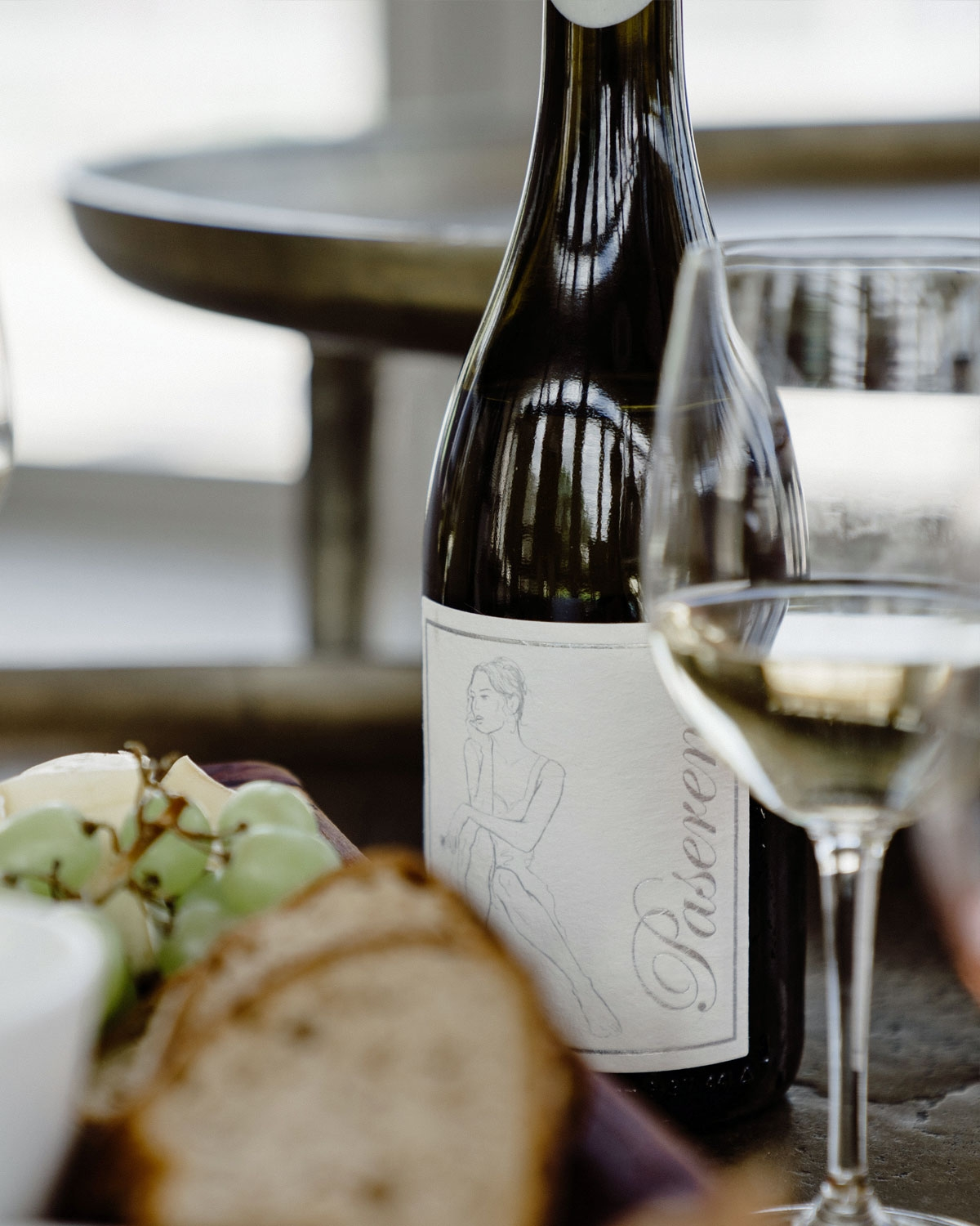 Eine Weißweinflasche mit einem minimalistischen Etikett, das die Strichzeichnung einer sitzenden Person und das Wort Slevene in vertikaler Schrift auf der rechten Seite zeigt.