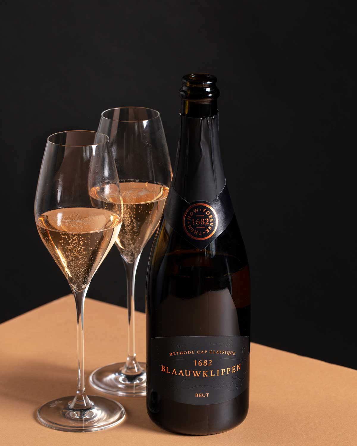 Eine Flasche Blaauwklippen Method Cap Classique Brut Sekt mit einem schwarz-goldenen Etikett mit der Aufschrift 1682 und Blaauwklippen auf der Vorderseite. Die Flasche ist mit schwarzer Folie versiegelt.