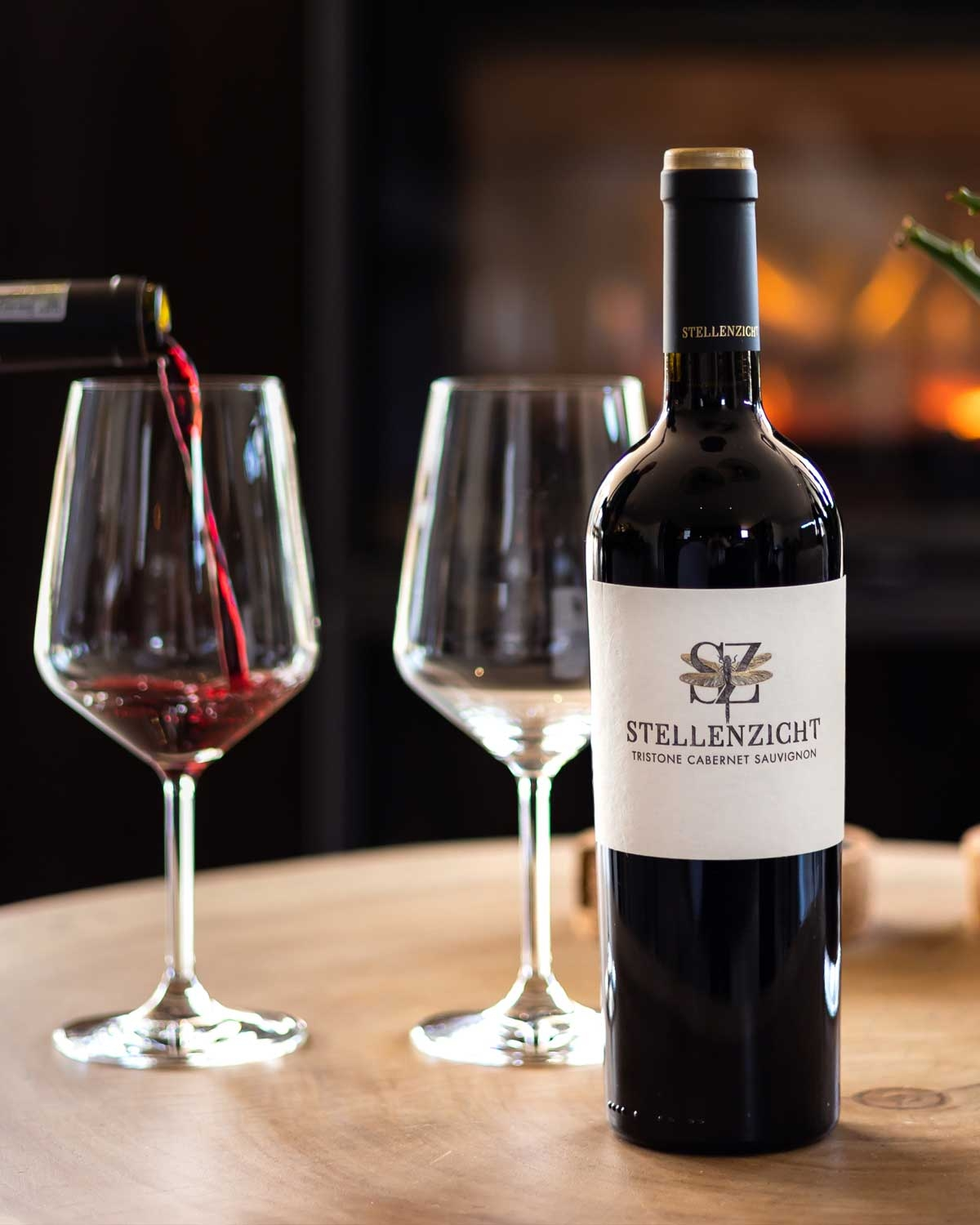 Eine Flasche Stellenzicht Tristone Cabernet Sauvignon Wein mit schwarzem Verschluss, cremefarbenem Etikett und gold-schwarzem Logo mit den Buchstaben "SZ" und einem geometrischen Muster.