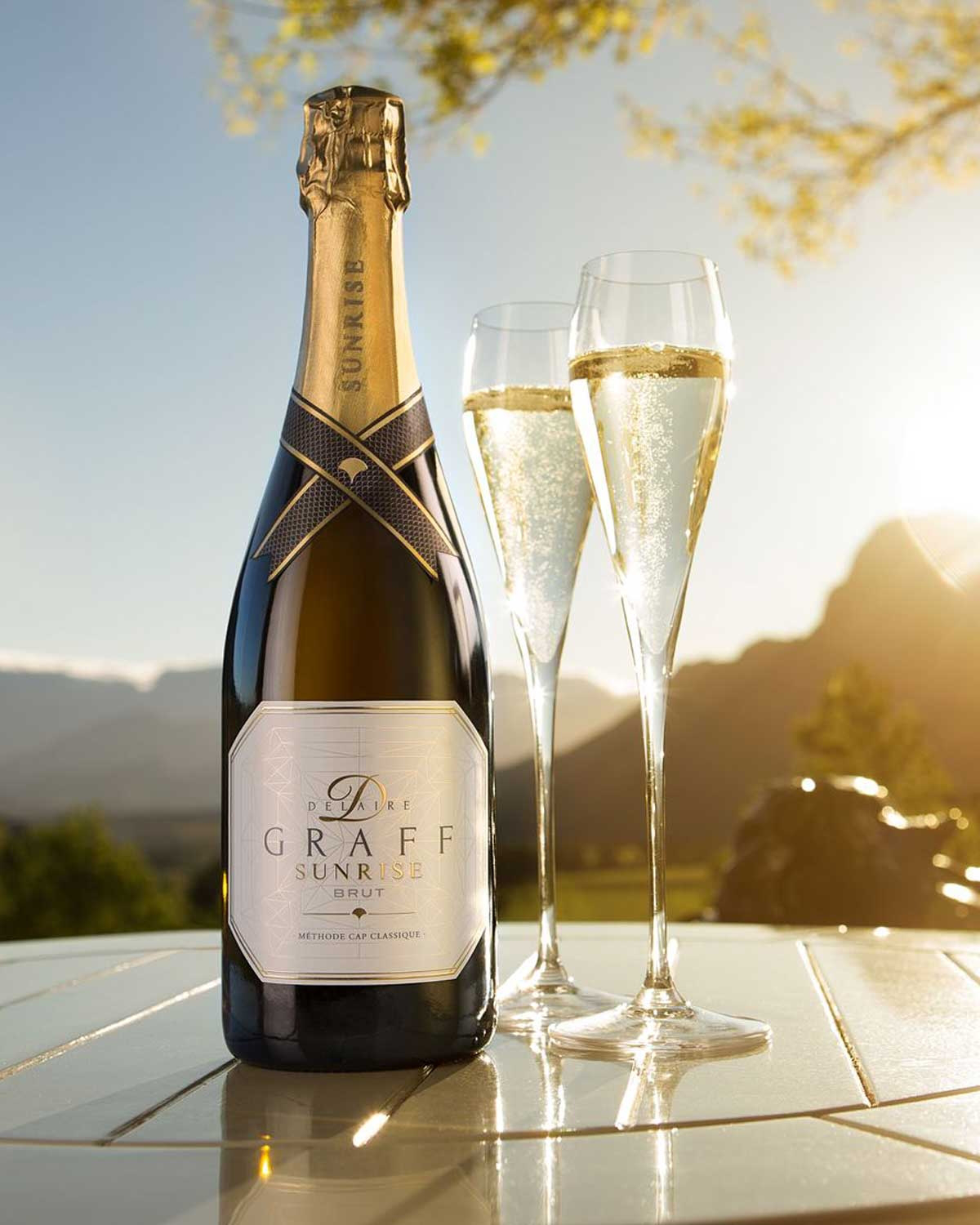 Eine Flasche Graham Beck Sunrise Brut Sekt mit einem goldenen Folienverschluss und einem geometrisch gemusterten Etikett mit dem Markennamen und Produktangaben.