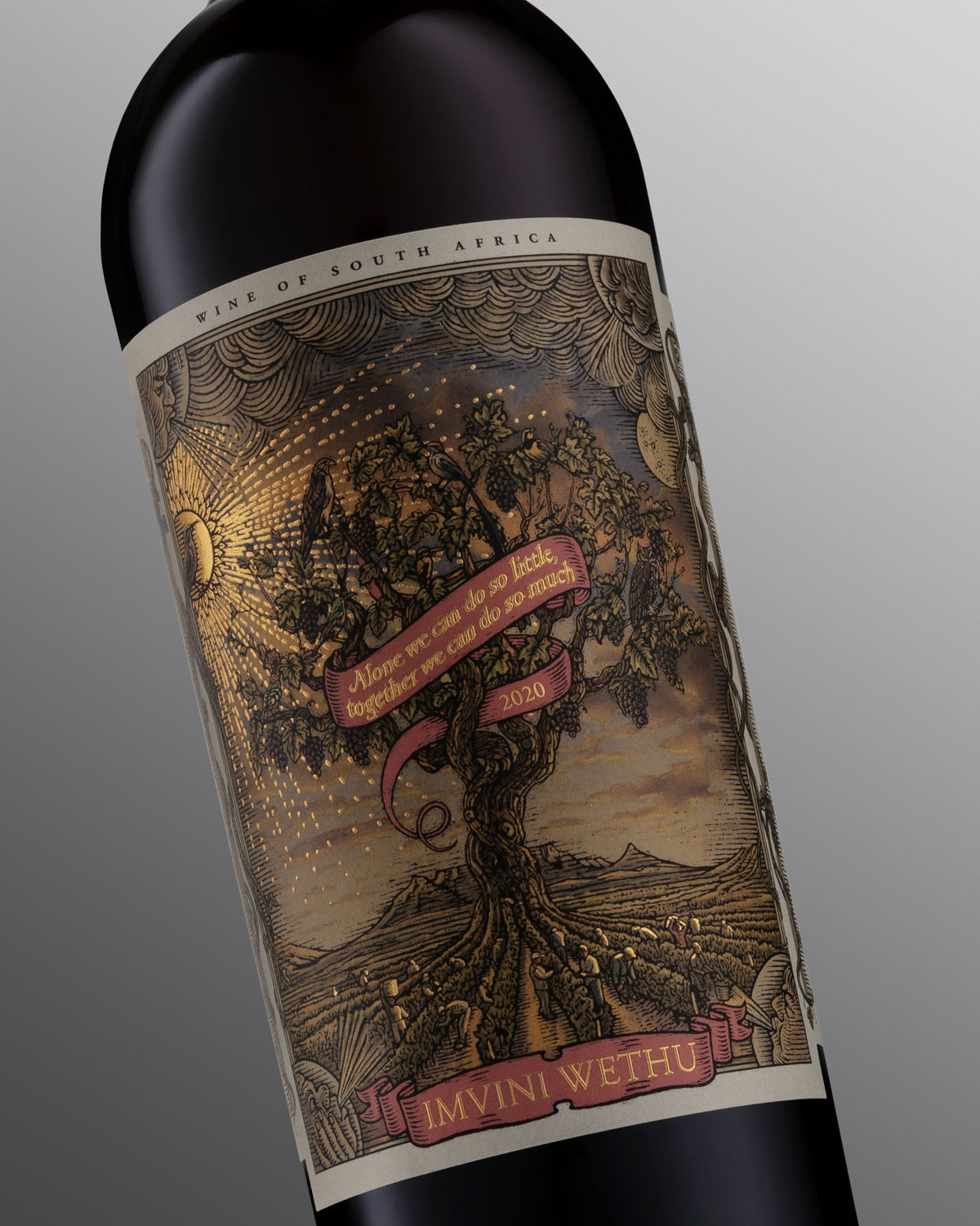 Eine dunkle Weinflasche mit einem kastanienbraunen Foliendach. Das Etikett zeigt einen illustrierten Baum mit einem Banner, auf dem zu lesen ist: "Allein können wir so wenig tun, gemeinsam so viel", und die Worte IMVINI WETHU am unteren Rand.