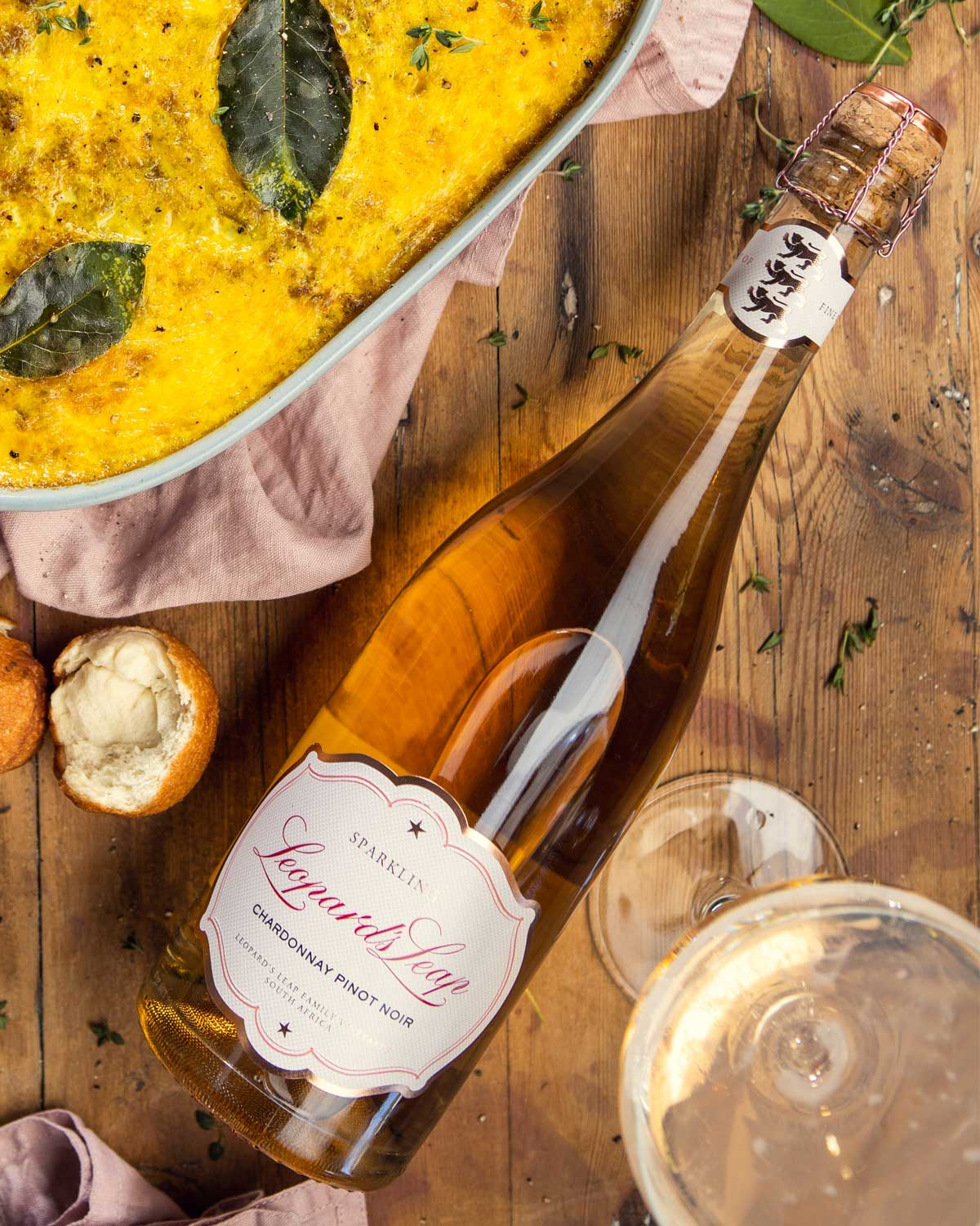 Eine Flasche Leopards Leap Sekt mit Korkverschluss und Drahtkäfig, mit einer blassrosa Flüssigkeit und einem weißen Etikett mit der Aufschrift Chardonnay Pinot Noir in eleganter Schrift.