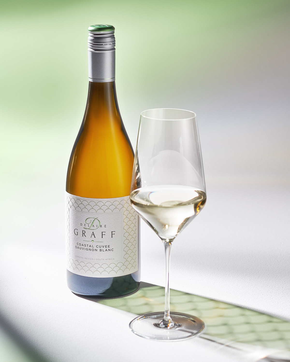 Eine Flasche Delaire Graff Coastal Cuvée Sauvignon Blanc mit einem silbernen Verschluss und einem weißen, gemusterten Etikett mit dem Markennamen und den Angaben zum Wein.