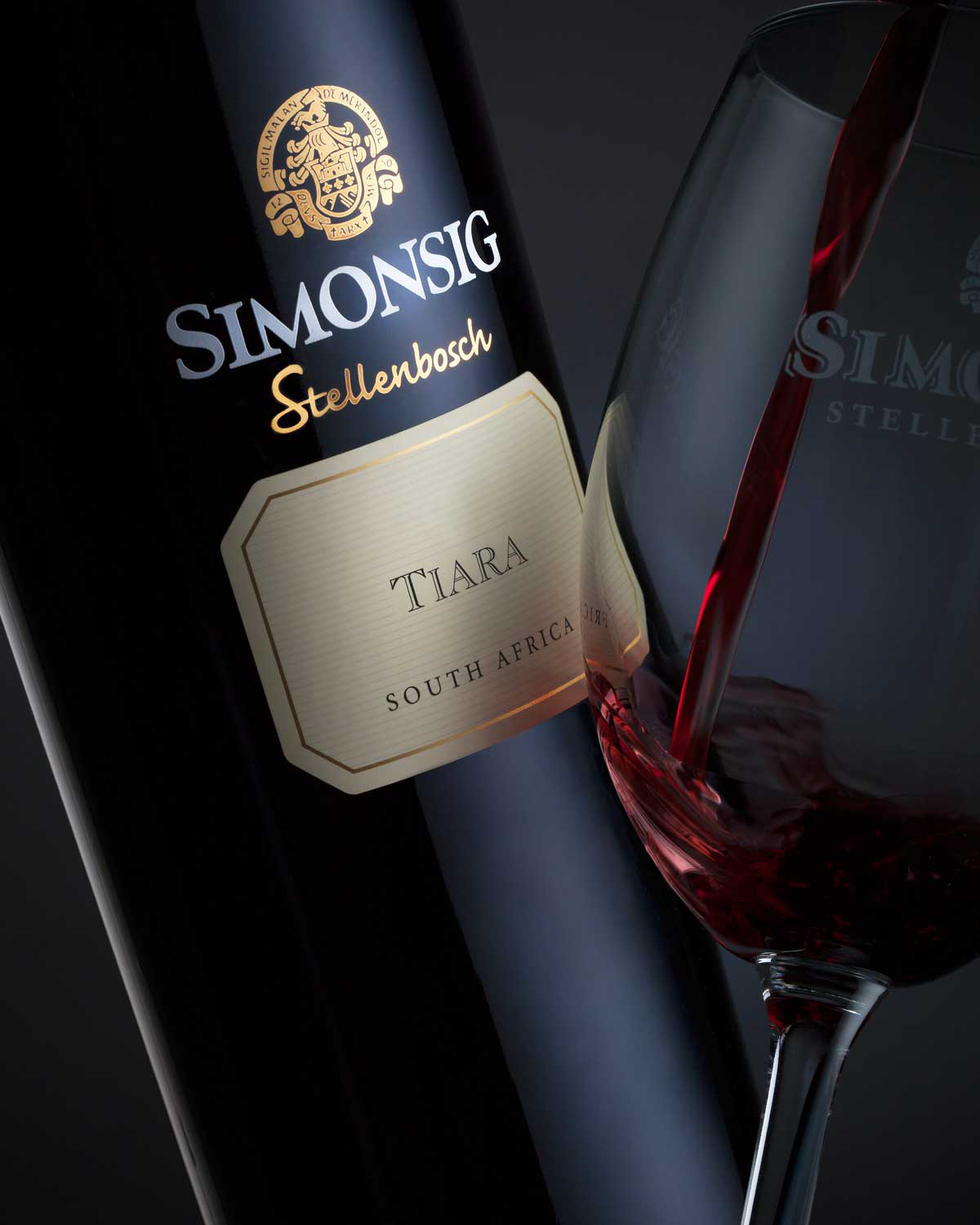 Eine dunkle Glasflasche von Simonsig Stellenbosch Tiara Rotwein aus Südafrika, mit einem goldenen und cremefarbenen Etikett mit dem Logo und Namen des Winzers.