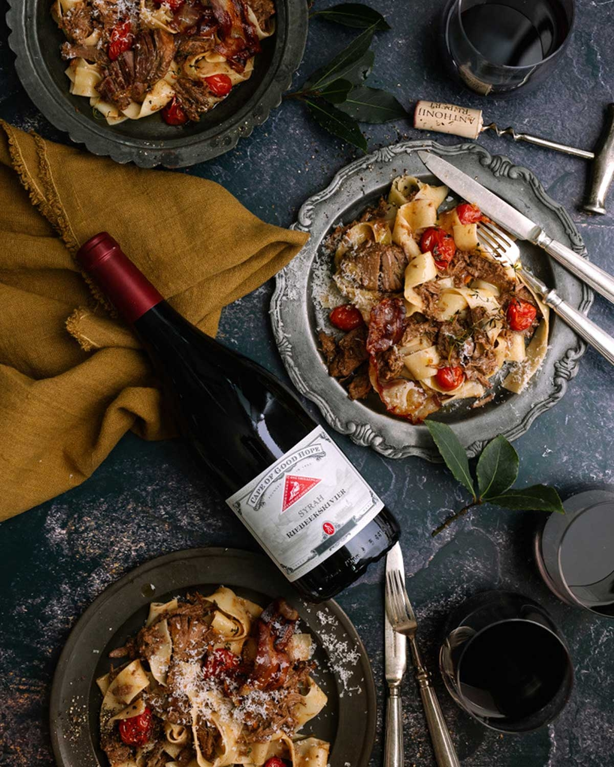 Eine dunkle Weinflasche mit rotem Foliendeckel, beschriftet mit Cape of Good Hope Syrah Riebeeksrivier Swartland. Das Etikett ist cremefarben mit einem roten Emblem und dekorativen Rändern.