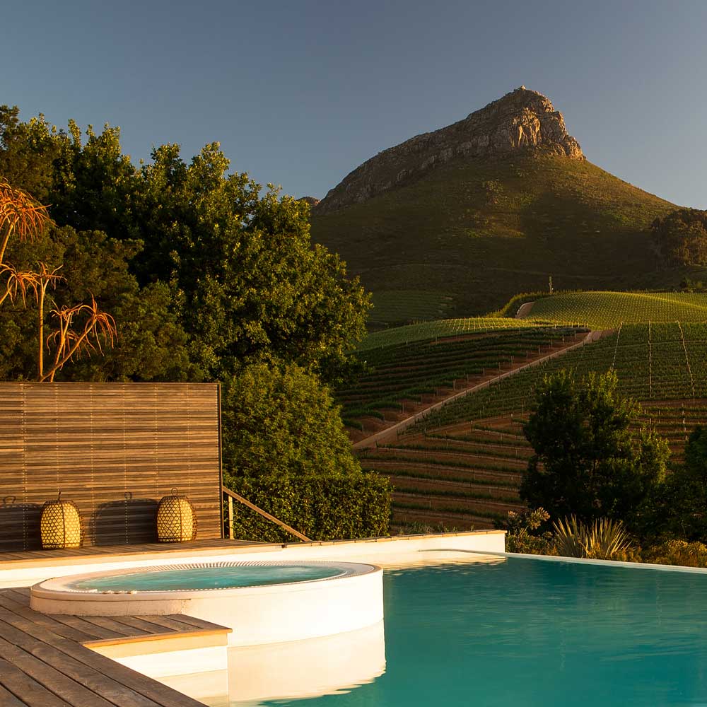 Infinity-Pool mit Blick auf Weinberge und Hügel bei Sonnenuntergang in Südafrika