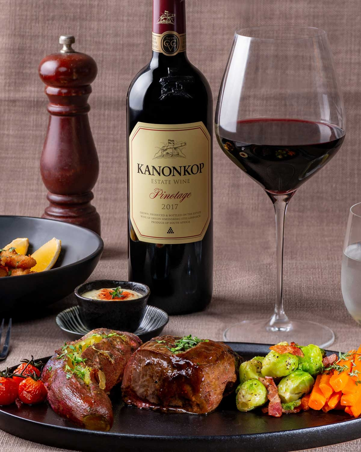 Eine Flasche Kanonkop Estate Wine Pinotage mit einem cremefarbenen Etikett, roter Kapsel und goldenen Akzenten. Auf dem Etikett ist eine Kanone abgebildet und der Text weist darauf hin, dass er in Stellenbosch, Südafrika, hergestellt wird.