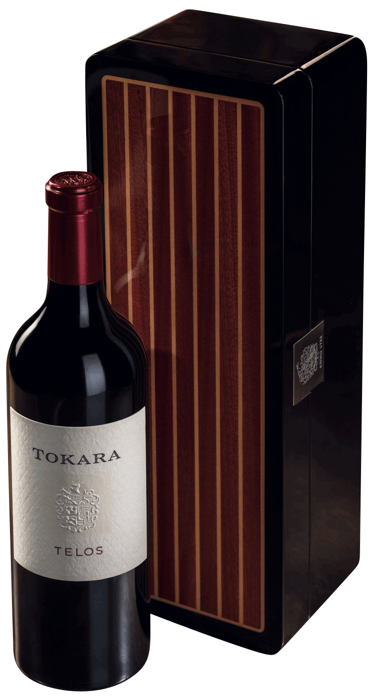 Eine Flasche Tokara Telos Rotwein mit rotem Foliendach steht neben einer eleganten schwarzen und holzgemusterten Geschenkbox.