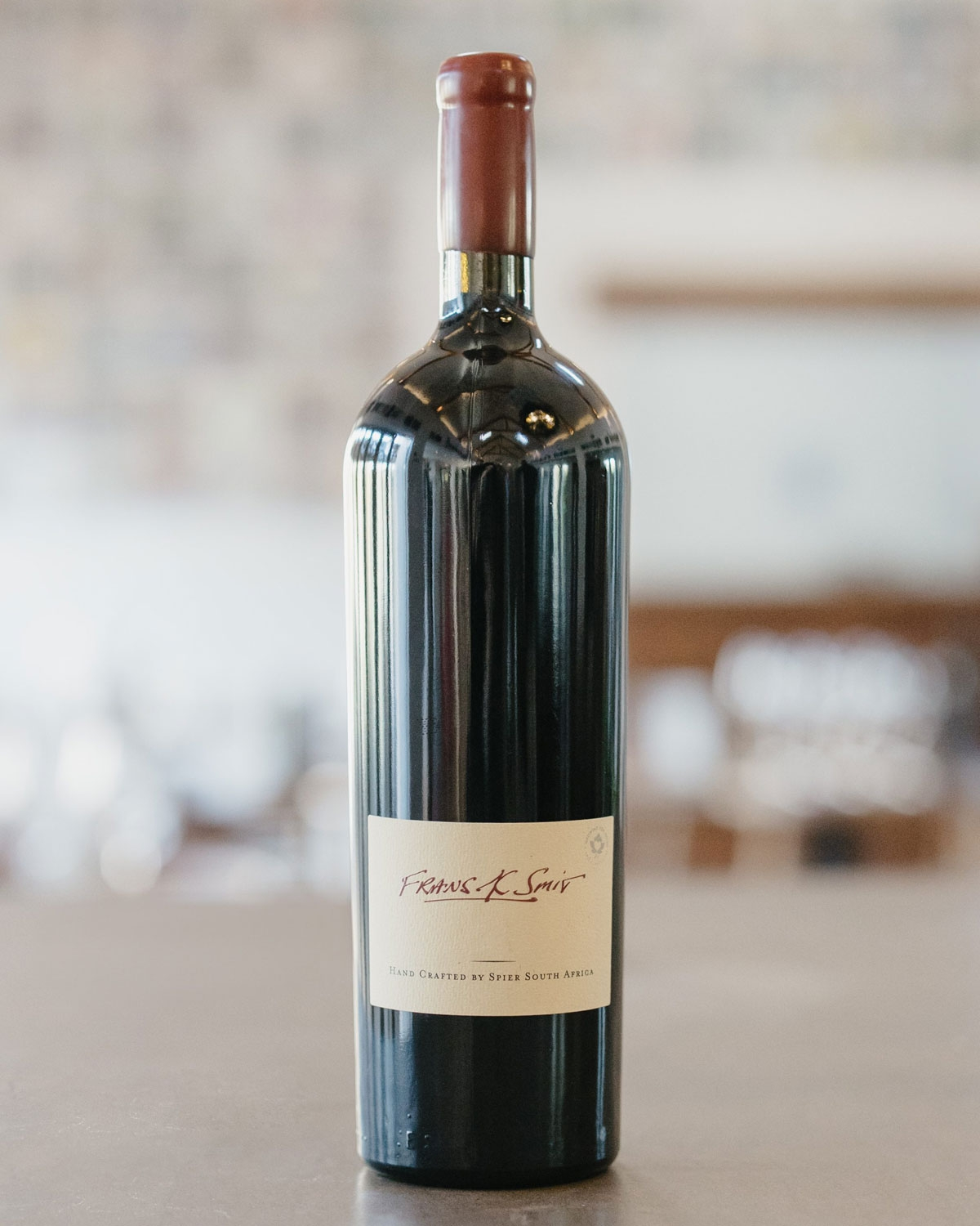 Eine Weinflasche aus dunklem Glas mit einem roten Wachssiegel auf dem Deckel und einem cremefarbenen Etikett mit der Aufschrift Francis K. Smit und Hand Crafted by Spier South Africa.