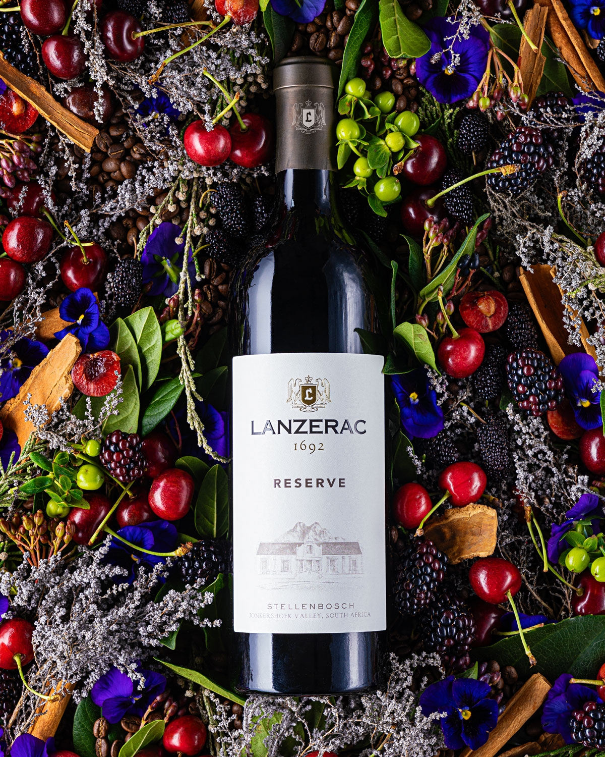 Eine Flasche Lanzerac Reserve Rotwein mit schwarzem Verschluss, weißem Etikett mit dem Lanzerac-Logo, 1692, und einer Abbildung eines Gebäudes. Auf dem Etikett steht außerdem Stellenbosch, Jonkershoek Valley, Südafrika.
