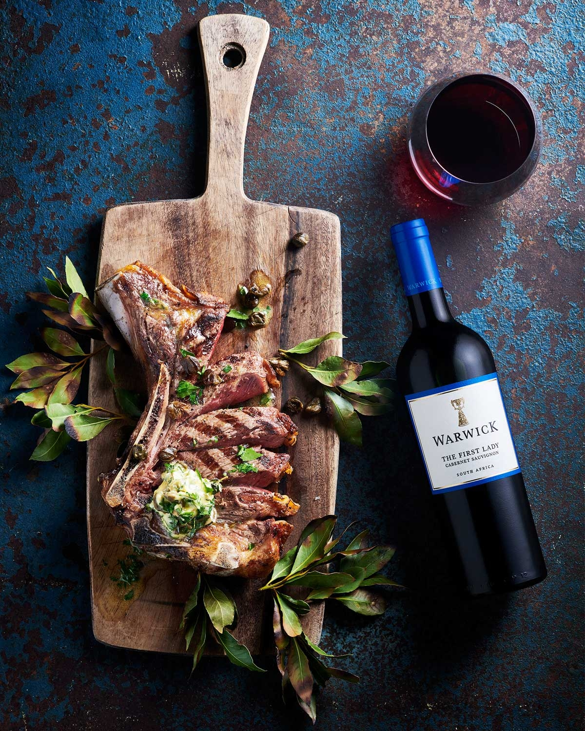 Eine Flasche Warwick The First Lady Cabernet Sauvignon Wein aus Südafrika mit blauem Verschluss und weißem Etikett mit blauem Rand und goldenen Akzenten.