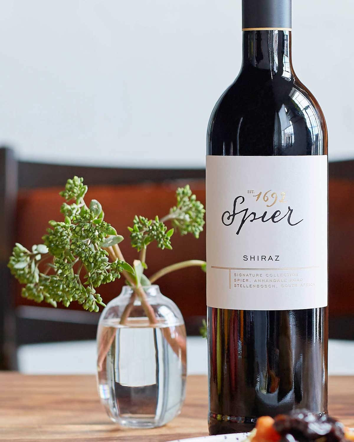 Eine Flasche Spier Shiraz Rotwein mit einem schwarzen Verschluss und einem weißen Etikett mit goldener und schwarzer Schrift. Auf dem Etikett steht das Spier-Logo, "Shiraz" und der Hinweis, dass er aus Südafrika stammt.