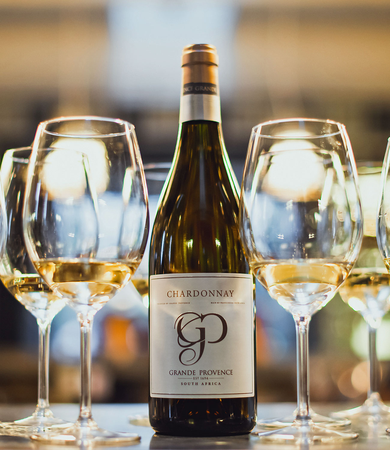 Eine Flasche Grande Provence Chardonnay Wein aus Südafrika mit einem weißen Etikett, auf dem in großen Buchstaben GP und oben Chardonnay steht. Die Flasche hat eine Goldfolie um den Hals.