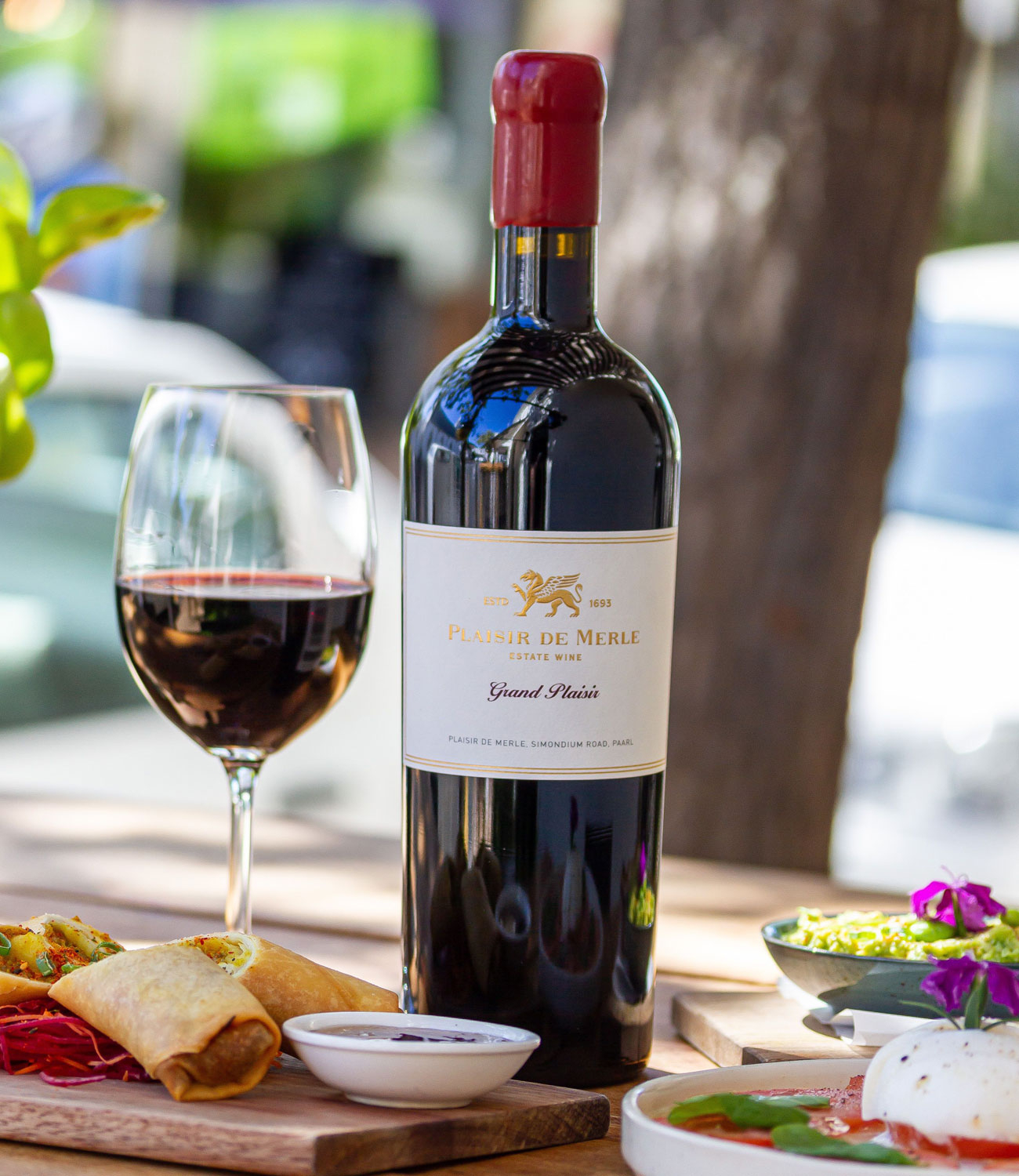 Eine Flasche Rotwein mit rotem Wachssiegel und einem weiß-goldenen Etikett mit der Aufschrift Plaisir de Merle Grand Plaisir Estate Wine aus Paarl, Südafrika.