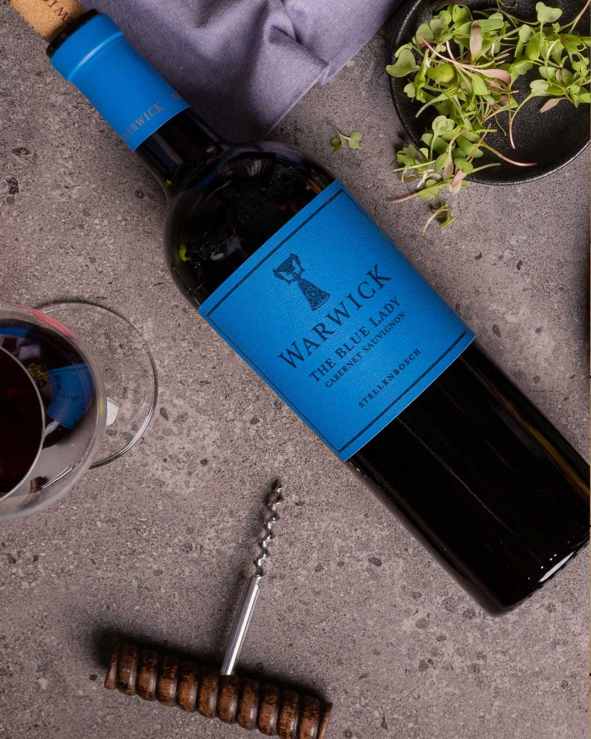 Eine Flasche Warwick The Blue Lady Cabernet Sauvignon aus Stellenbosch mit blauem Etikett und blauem Folienverschluss mit Text und Trophäenlogo.
