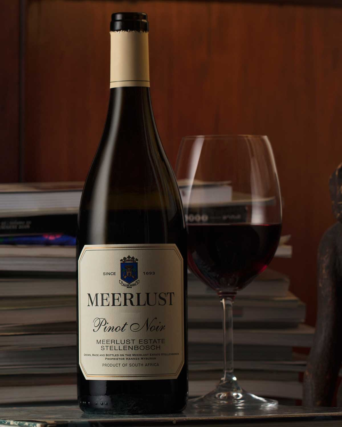 Eine Flasche Meerlust Pinot Noir-Wein mit cremefarbenem Etikett, blau-goldenem Wappen und einem Text, der darauf hinweist, dass er vom Meerlust Estate in Stellenbosch, Südafrika, stammt.