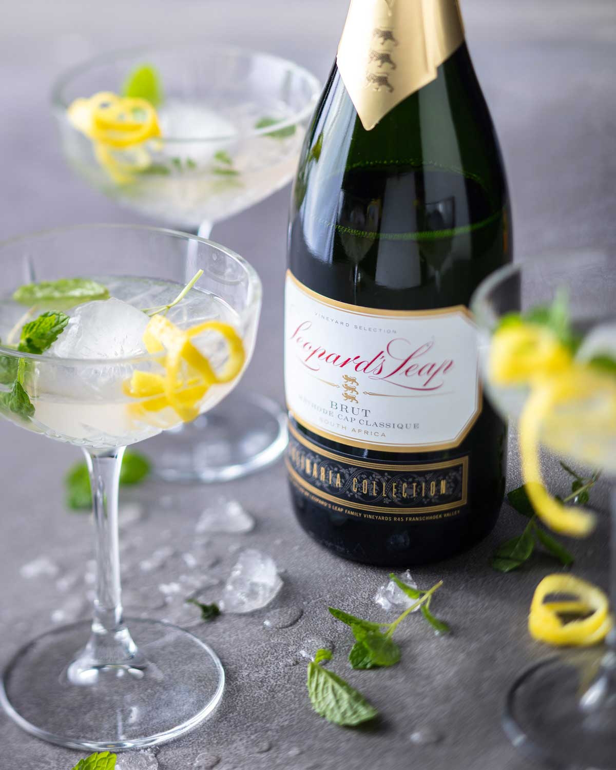 Eine Flasche Leonard's Leap Brut Schaumwein aus Südafrika mit einem mit Goldfolie umwickelten Hals und einem schwarzen Etikett mit goldenen Akzenten am unteren Teil der Flasche.