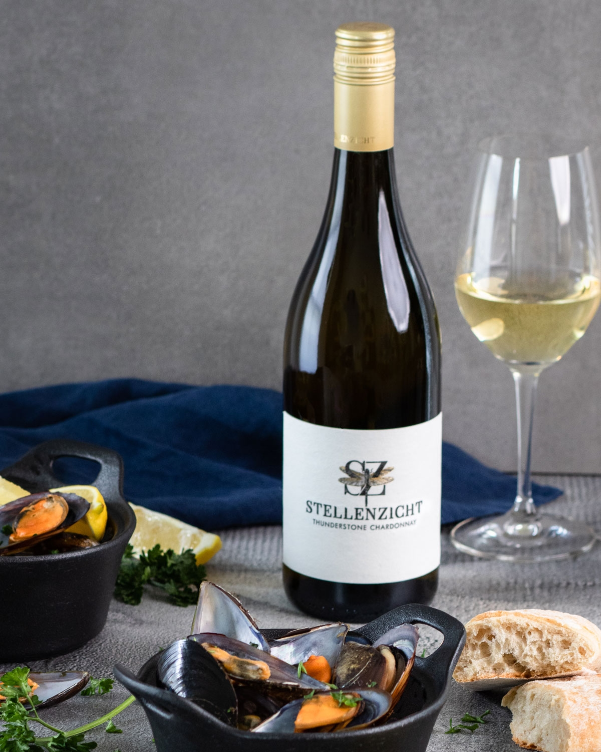 Eine Flasche Stellenzicht Thunderstone Chardonnay mit goldenem Schraubverschluss, weißem Etikett mit Libellenmotiv und schwarzem Text, der den Namen und die Sorte des Weins angibt.