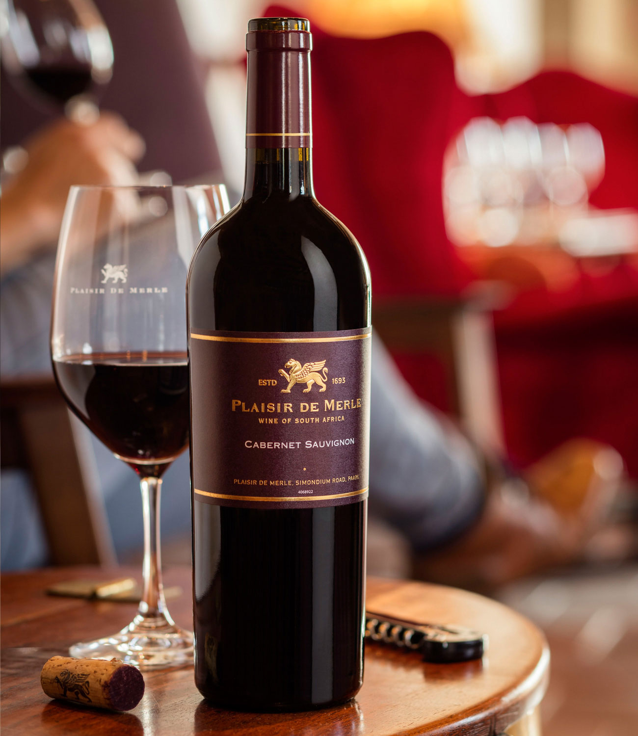 Eine dunkle Weinflasche mit der Aufschrift Plaisir de Merle Estate Wine Cabernet Sauvignon mit goldenen Akzenten und einem kastanienbraunen Verschluss. Das Etikett zeigt ein geflügeltes Pferd und einen Text, der angibt, dass der Wein aus Paarl, Südafrik