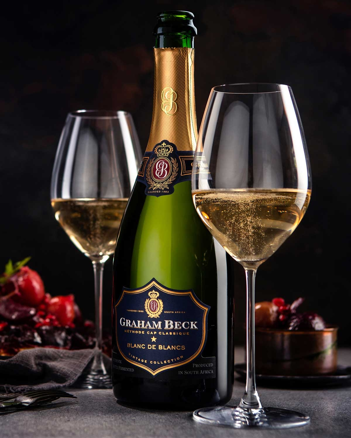 Eine Flasche Graham Beck Blanc de Blancs Sekt mit Goldfolie am Hals und einem dunkelblau-goldenen Etikett mit dem Markennamen und Details.