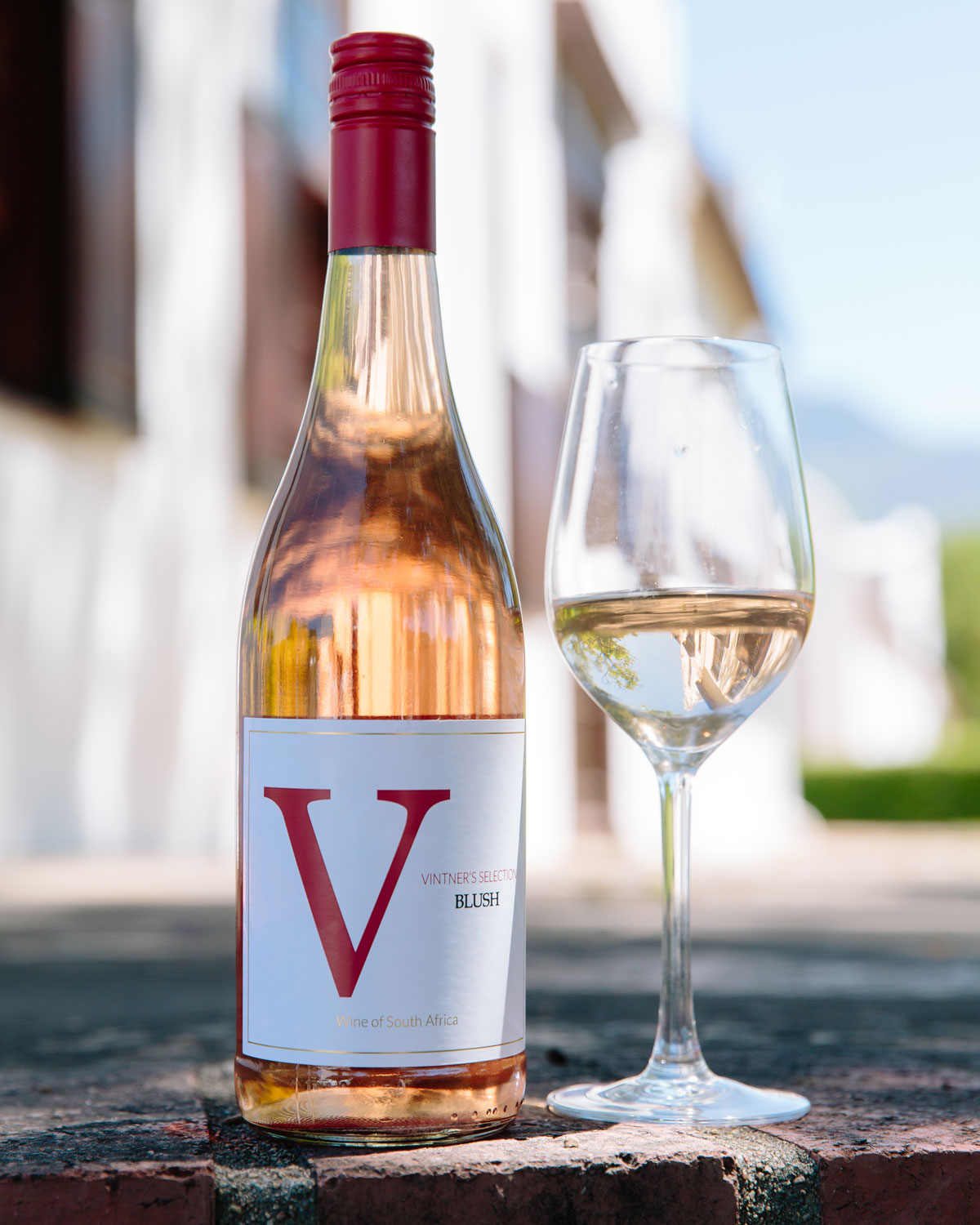 Eine Flasche Capreo Vintners Selection Blush Wein aus Südafrika. Die Flasche hat einen roten Schraubverschluss und ein weißes Etikett mit einem großen roten V und Text, der angibt, dass es sich um einen Blush-Wein handelt.