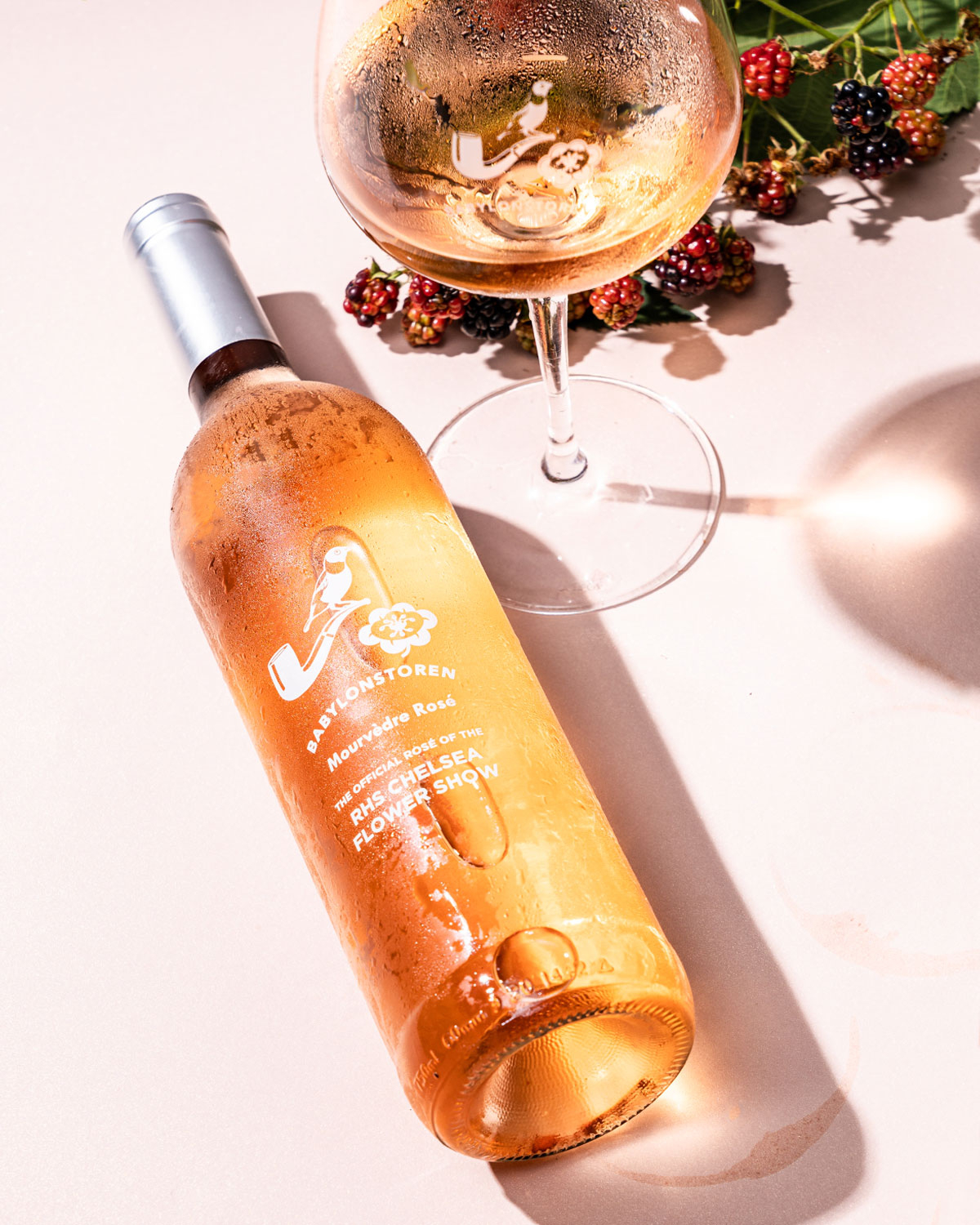 Eine Klarglasflasche Babylonstoren Mourvèdre Rosé mit weißem Etikett mit Vogel- und Blumenmotiv und dem Text, dass es sich um den offiziellen Rosé der RHS Chelsea Flower Show handelt.