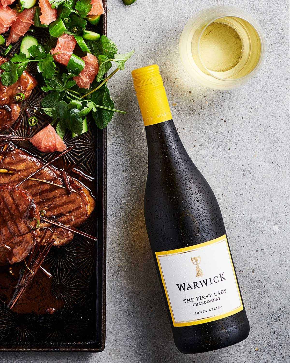 Eine Flasche Warwick The First Lady Chardonnay mit einem gelben Verschluss und einem weißen Etikett, auf dem das Warwick-Logo, der Name des Weins und der Schriftzug South Africa zu lesen sind.