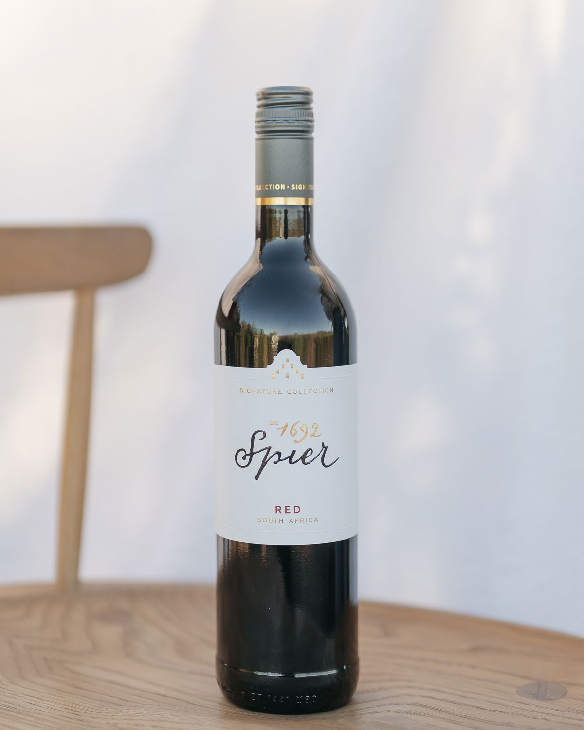 Eine Flasche Spier Signature Collection Rotwein aus Südafrika mit einem weiß-goldenen Etikett mit schwarz-goldener Schrift und einem Schraubverschluss.
