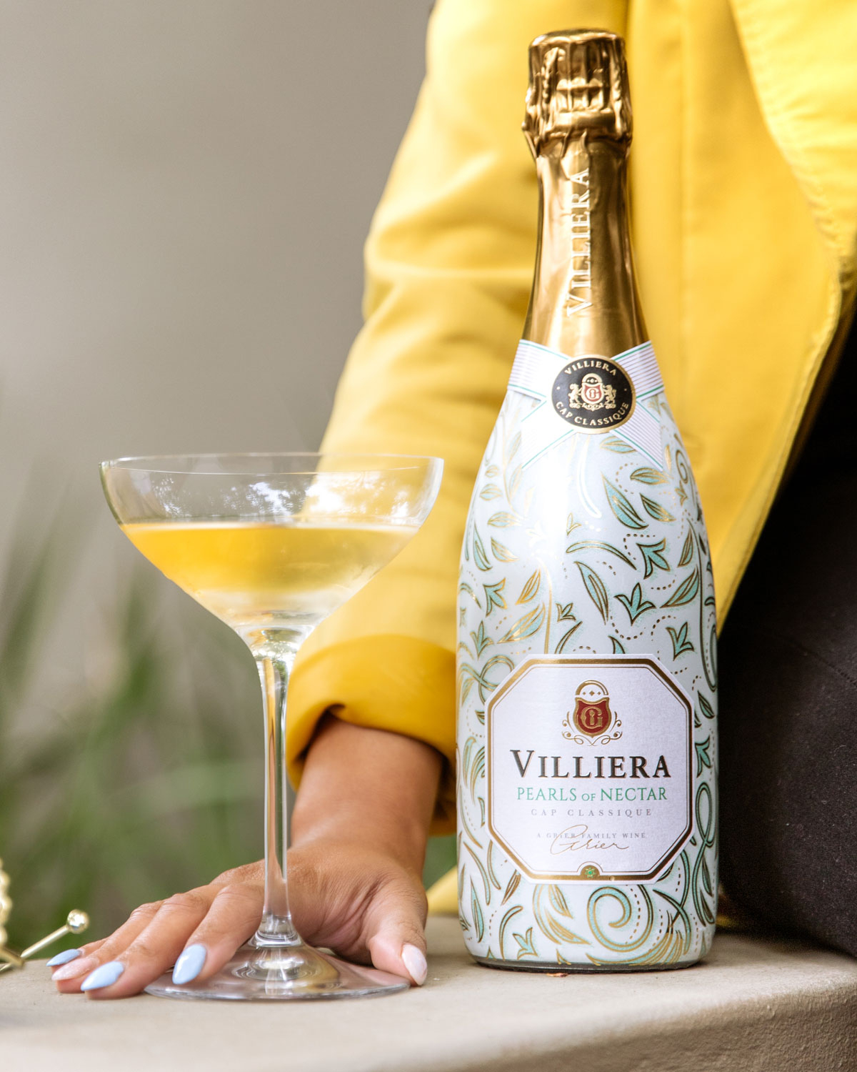 Eine Flasche Villiera Pearls of Nectar Sekt mit Goldfolienverschluss, weiß-goldenem Schmucketikett und elegantem Blattmuster auf der Flasche.