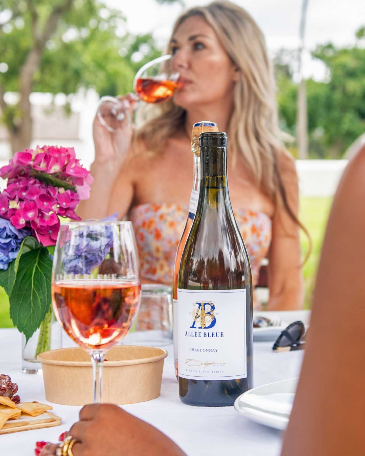 Eine Flasche Allée Bleue Chardonnay Wein mit blauem Verschluss und weißem Etikett mit goldener und blauer Aufschrift. Auf dem Etikett steht Allée Bleue Chardonnay und weist darauf hin, dass es sich um einen Wein aus Südafrika handelt.
