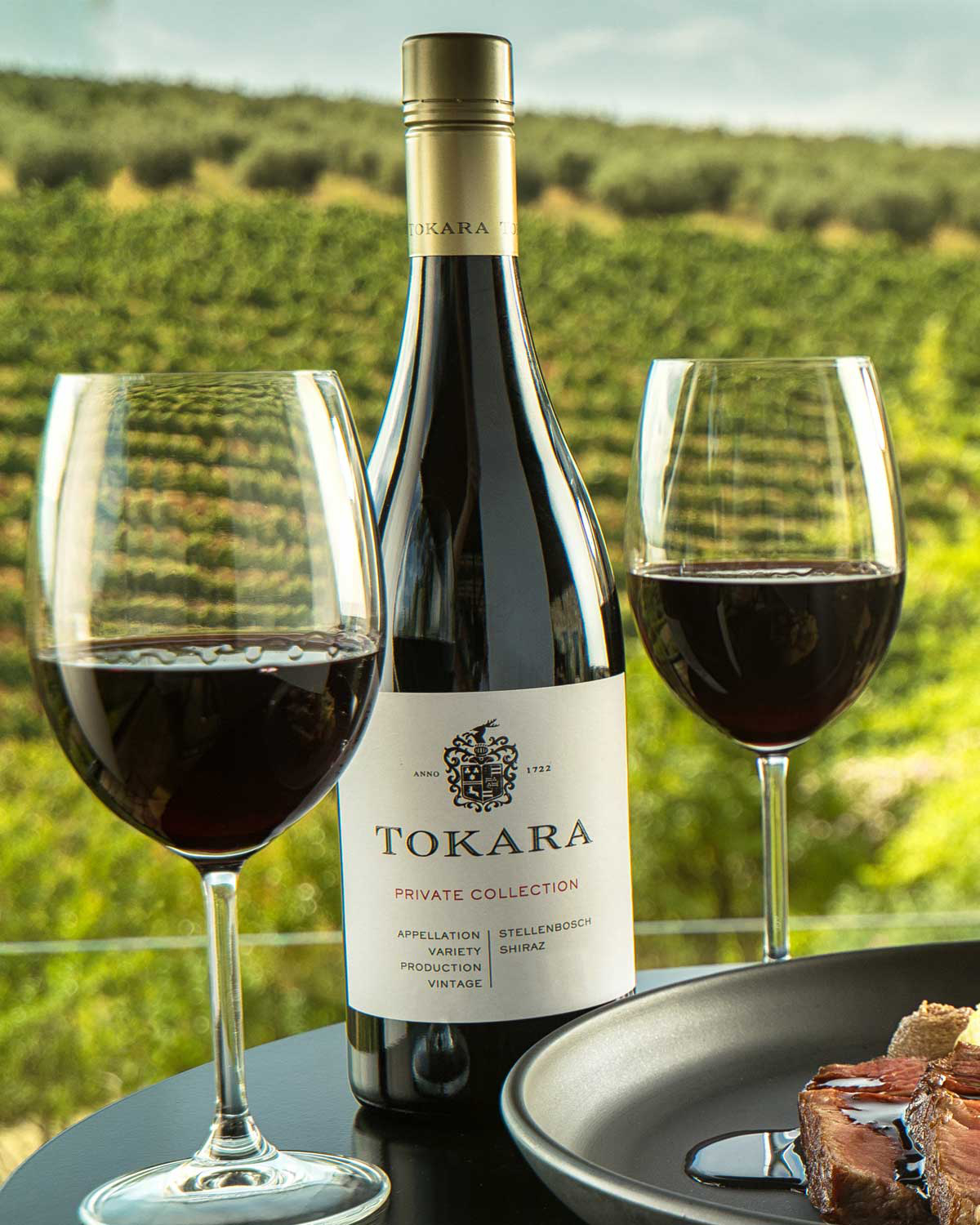 Eine Flasche Tokara Private Collection Stellenbosch Shiraz mit einem silbernen Verschluss und einem weißen Etikett mit dem Tokara-Logo und Weinangaben in schwarzer und roter Schrift.