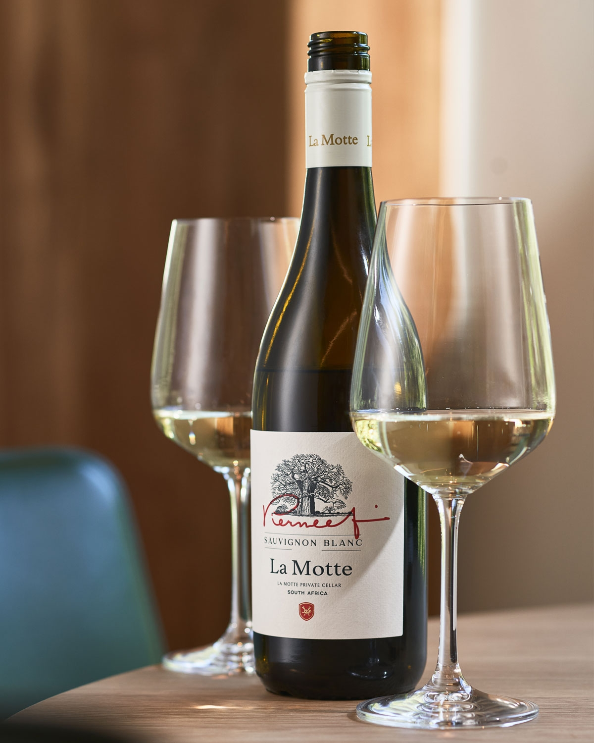 Eine Flasche La Motte Sauvignon Blanc mit weißem Etikett, auf dem ein Baum, rote Schreibschrift und der Text La Motte Private Cellar, South Africa abgebildet sind. Die Flasche hat einen weißen Schraubverschluss.
